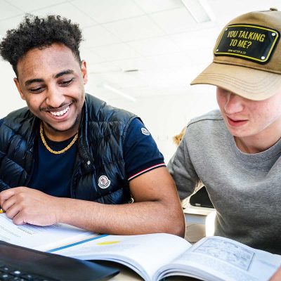 Två elever läser i läroböcker i ett klassrum.