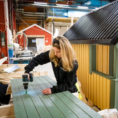 Elev jobbar med skruvdragare i en verkstad.
