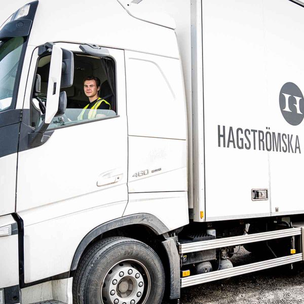 En elev kör lastbil och ler mot kameran.