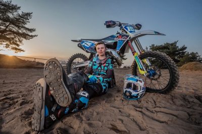 En elev sitter i lera framför en motorcross.
