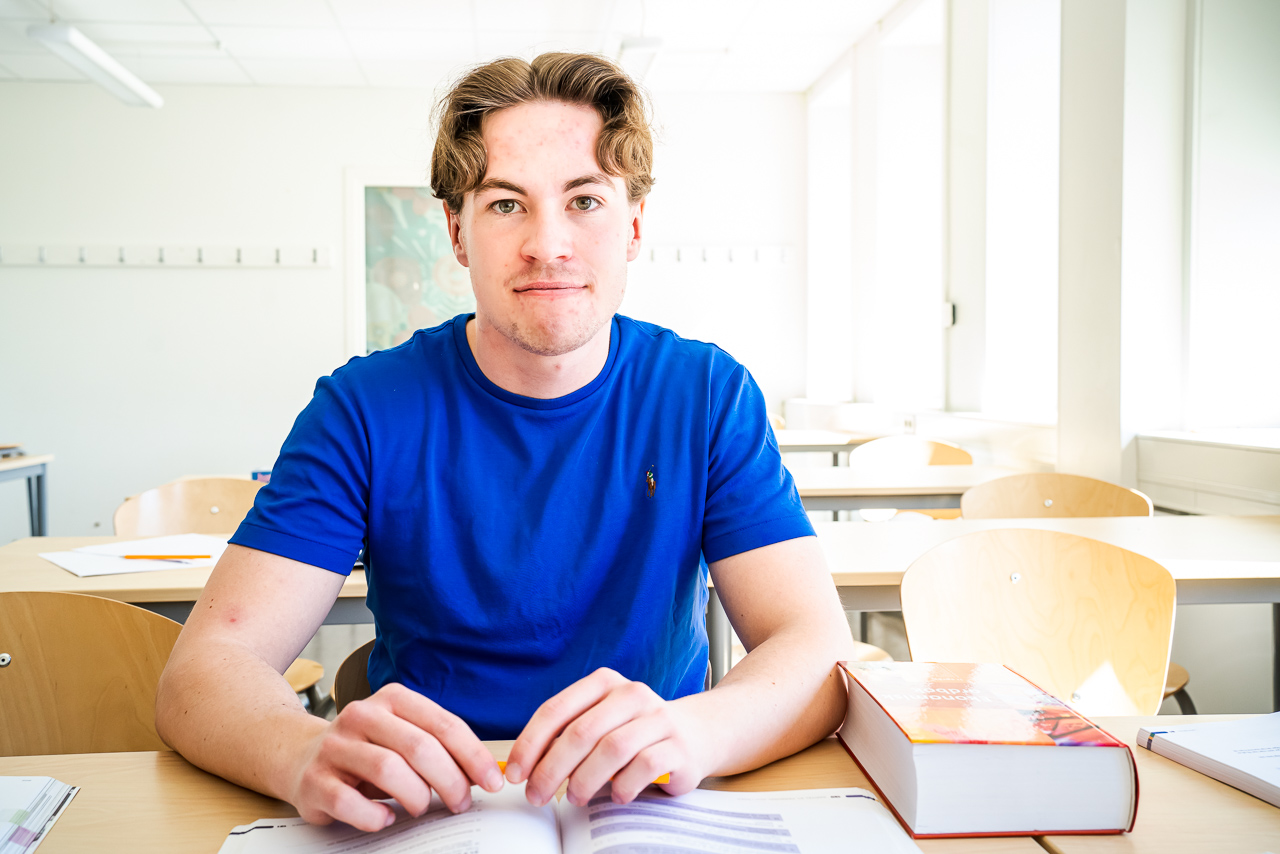 Elev i blå tröja i ett klassrum tittar in i kameran.