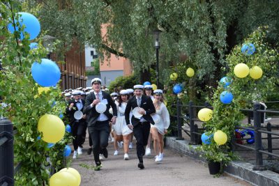 Elever som tar studenter och springer ut på en bro.