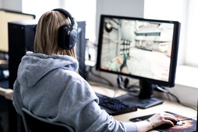 En e-sportselev med hörlurar spelar spel på en dator.