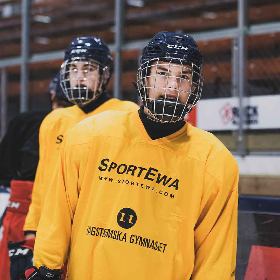 Två elever med hockeyutrustning är påväg ut på isen.