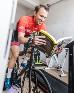 En person cyklar på en stationär träningscykel och läser en bok samtidigt.