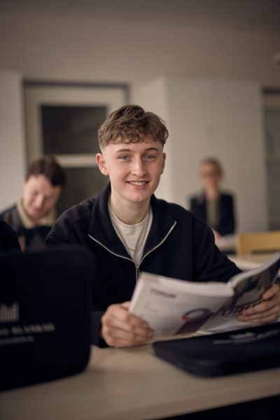 Elev på samhällsprogrammet som läser en bok i klassrummet.