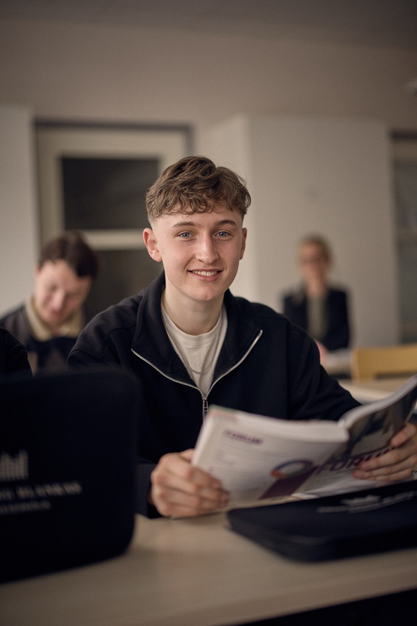 Elev på samhällsprogrammet som läser en bok i klassrummet.